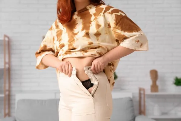 Image of woman trying to do her trousers up after pregnancy weight gain Nottinghamshire