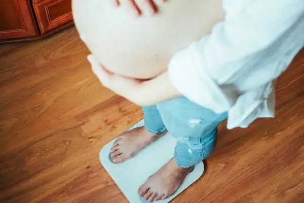 Image of woman weighing herself and experiencing weight gain through pregnancy Nottinghamshire